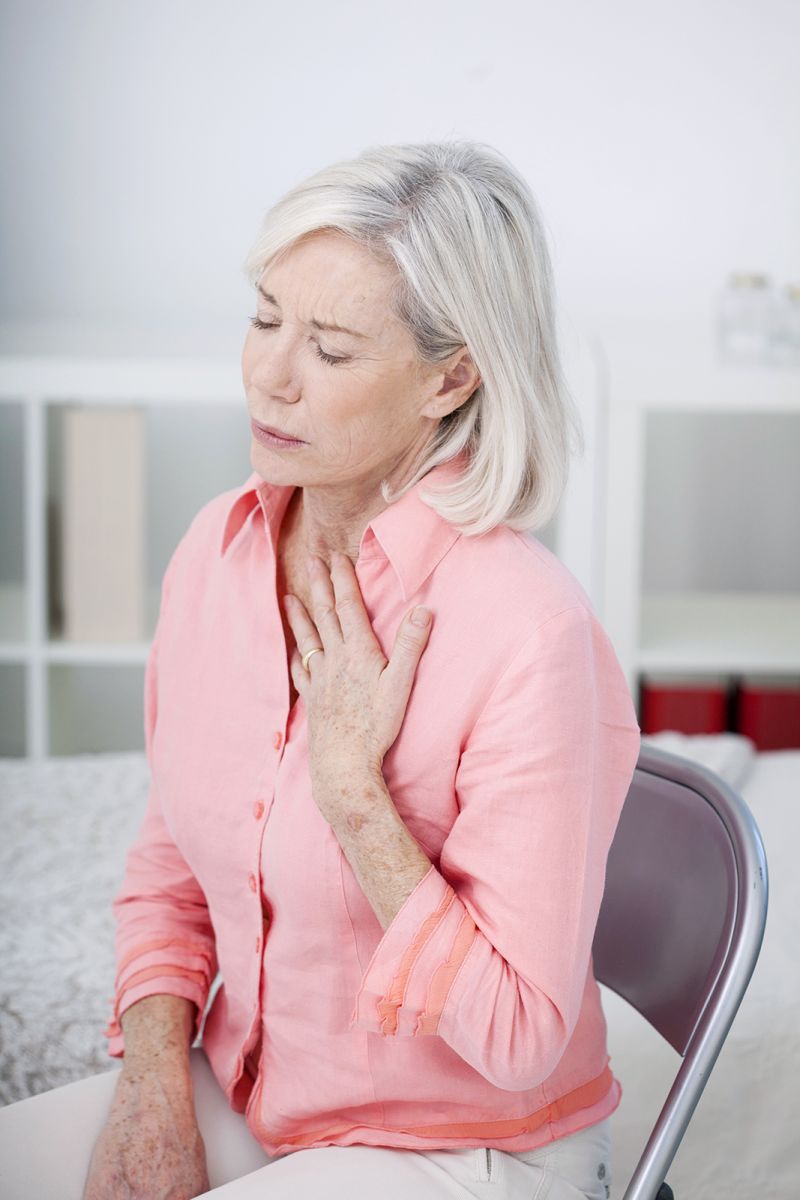 elderly woman putting hand on chest having trouble breathing