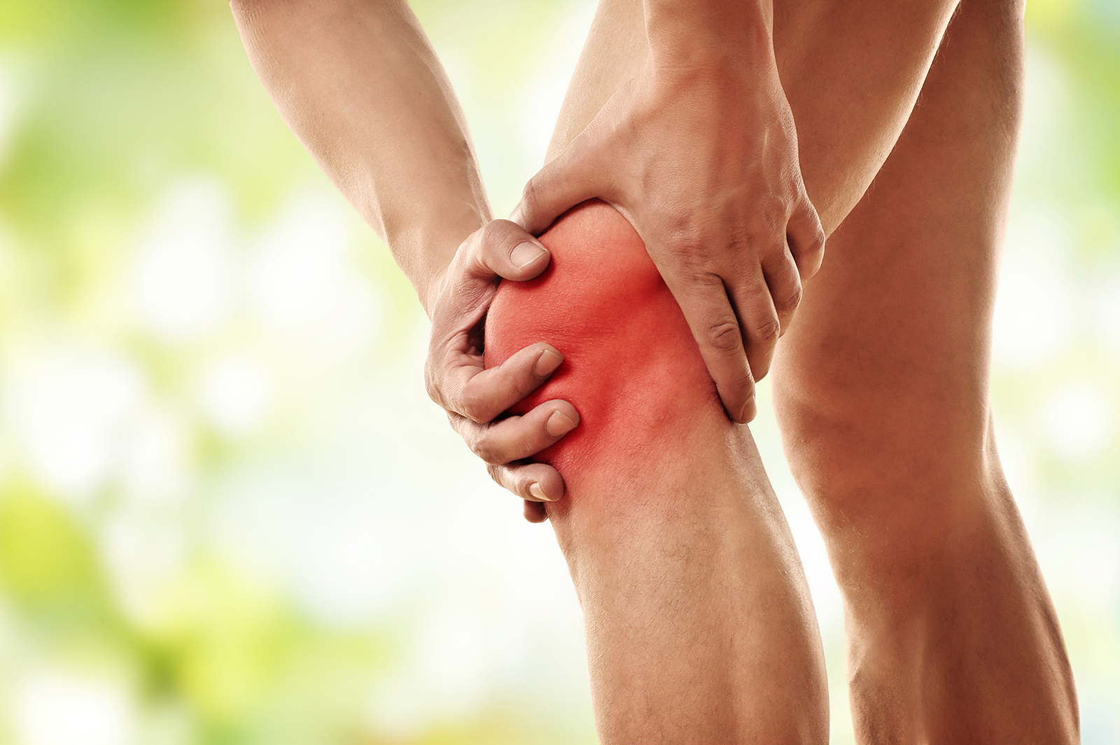 close up of man in pain holding knee that is bright red with both hands