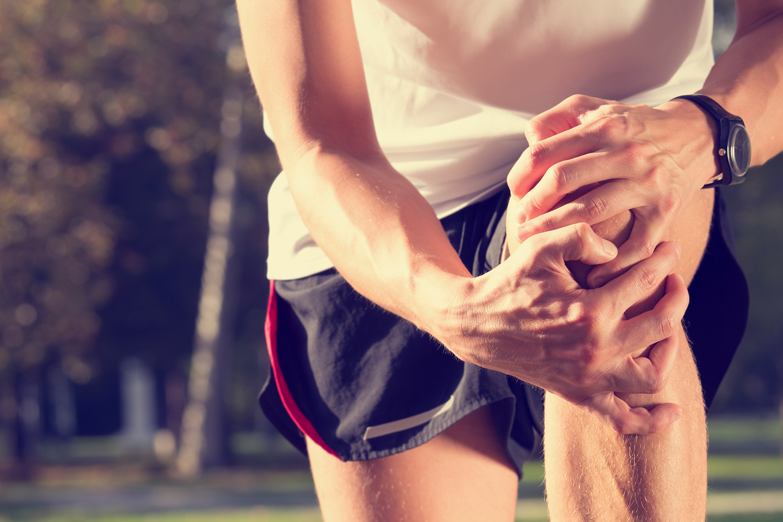 male runner holding knee with both hands