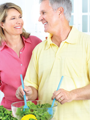 couple making salad and smiling at each other