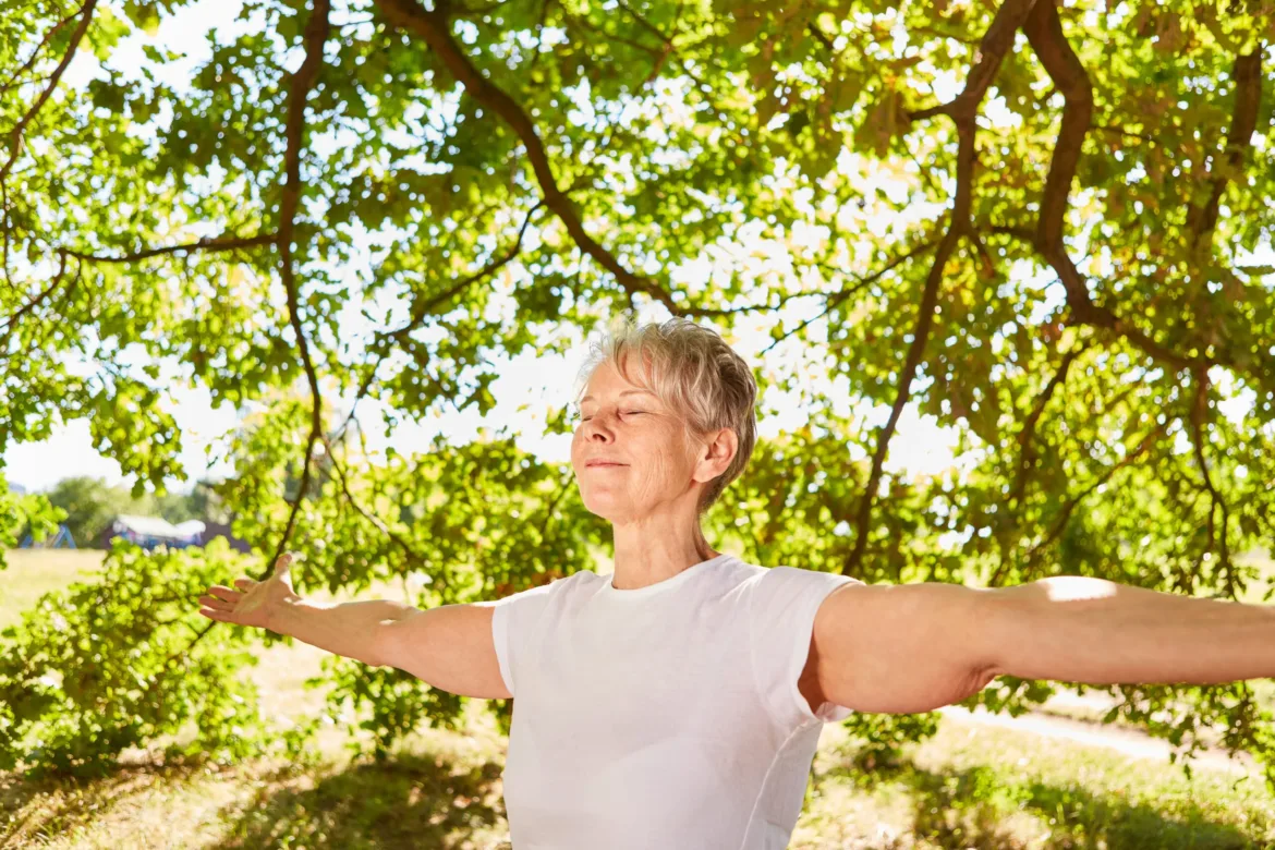 Happy elderly woman with arms outstretched doing a meditation and breathing exercise