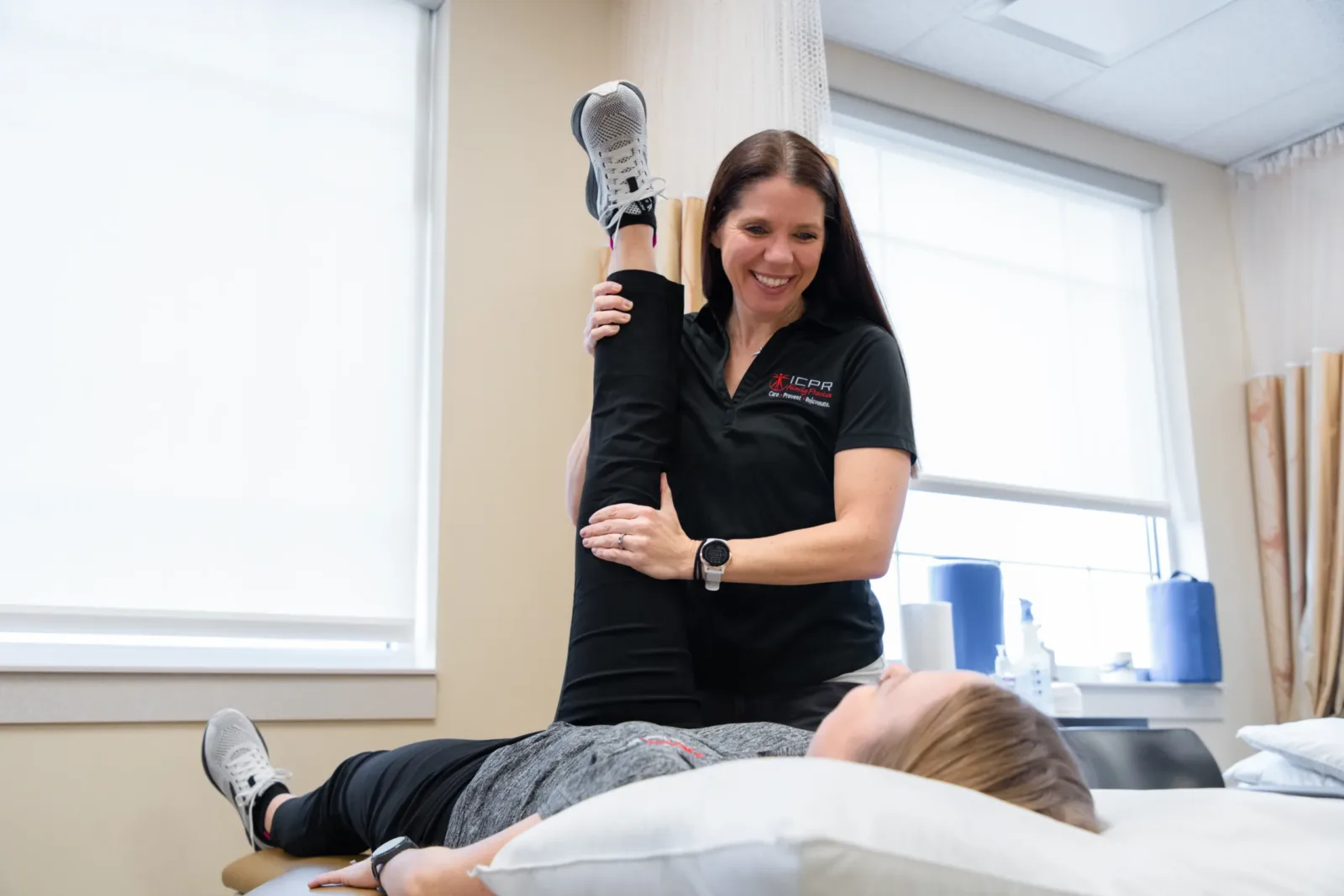 Physical therapist helping a patient stretch out her hamstrings